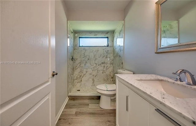 bathroom featuring tiled shower, hardwood / wood-style floors, vanity, and toilet