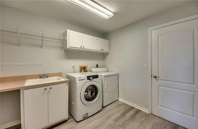 clothes washing area featuring cabinets, sink, light hardwood / wood-style flooring, and independent washer and dryer