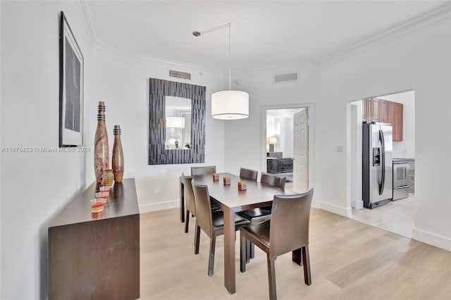 dining area with light hardwood / wood-style floors and ornamental molding