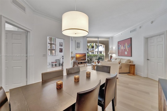 dining area with visible vents, light wood-style floors, and ornamental molding