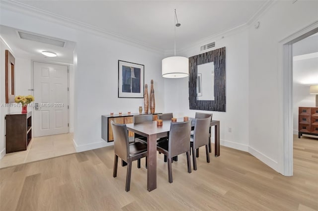 dining room with light hardwood / wood-style floors and crown molding