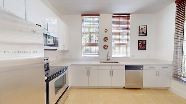 kitchen with white cabinetry, light countertops, a sink, light tile patterned flooring, and appliances with stainless steel finishes