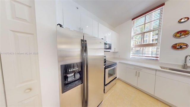 kitchen with light tile patterned flooring, light countertops, a sink, appliances with stainless steel finishes, and white cabinets