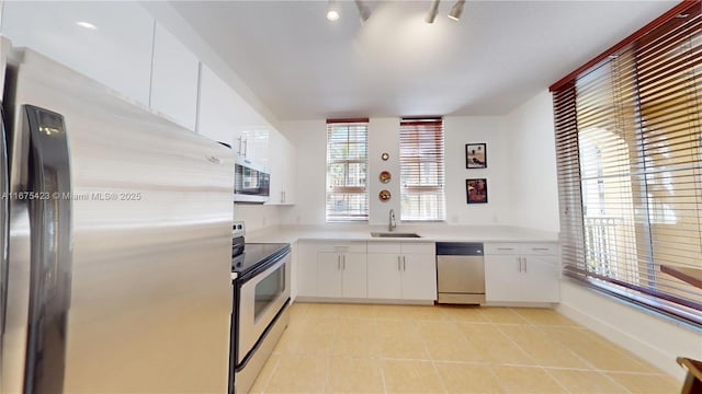 kitchen featuring white cabinetry, light countertops, light tile patterned floors, a sink, and appliances with stainless steel finishes