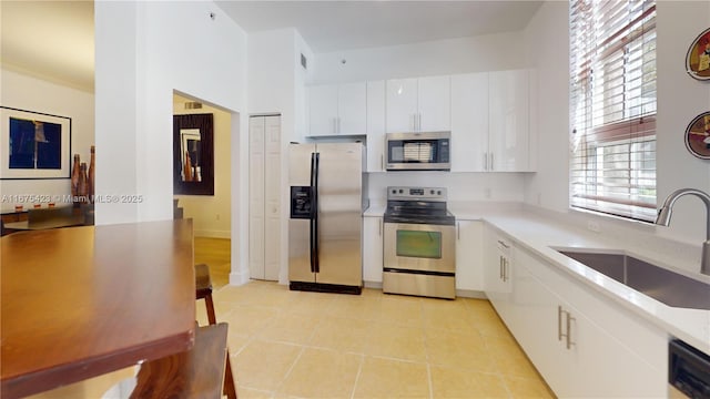 kitchen with light tile patterned flooring, light countertops, a sink, and stainless steel appliances