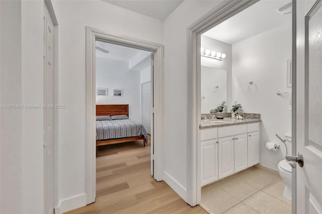 bathroom with vanity, toilet, baseboards, ensuite bath, and wood finished floors
