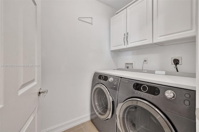 clothes washing area featuring light tile patterned floors, washing machine and dryer, and cabinets