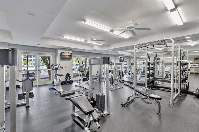 gym with ceiling fan and a raised ceiling