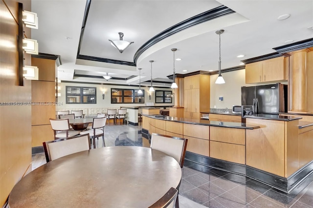 kitchen featuring light brown cabinets, a tray ceiling, a center island, decorative light fixtures, and black fridge with ice dispenser