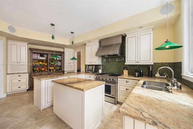 kitchen featuring a kitchen island, wall chimney exhaust hood, high end stainless steel range oven, sink, and pendant lighting