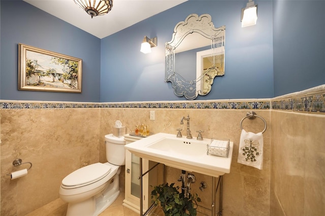 bathroom with toilet, sink, tile walls, and tile patterned flooring