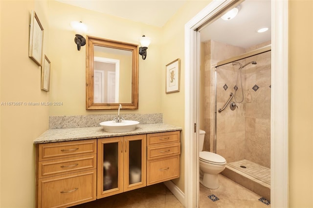 bathroom featuring a shower with door, vanity, toilet, and tile patterned floors