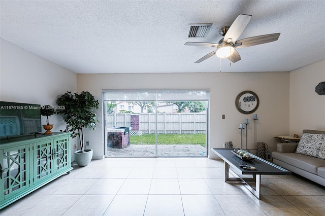 living area featuring tile patterned floors, visible vents, a textured ceiling, and a ceiling fan