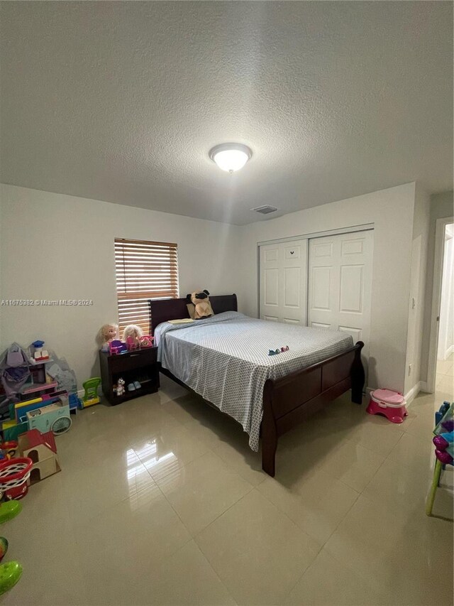 1369 Rainbow Ave, Palm Beach, FL 33406 - bedroom with a textured ceiling, light tile patterned floors, and a closet