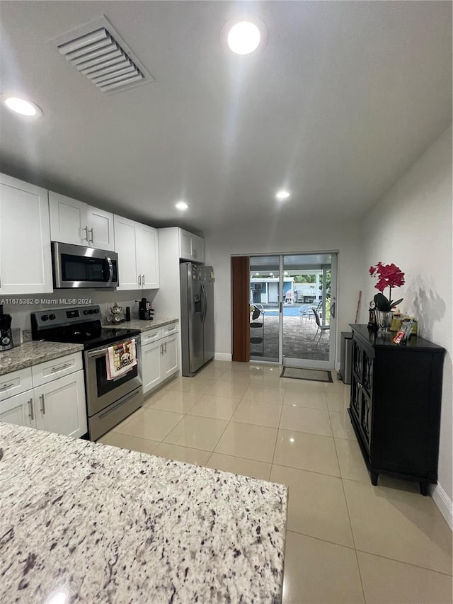 1369 Rainbow Ave, Palm Beach, FL 33406 - kitchen with stainless steel appliances, white cabinetry, recessed lighting, light stone counters, and light tile patterned floors