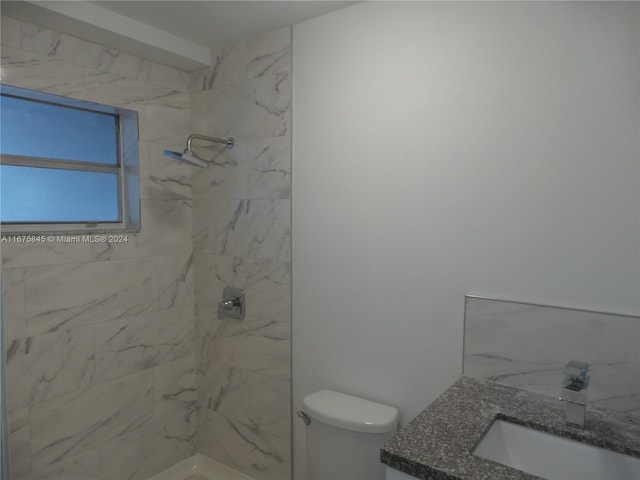 bathroom featuring vanity, a tile shower, and toilet