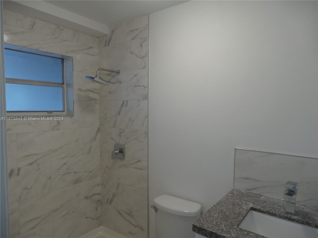 bathroom featuring vanity, tiled shower, and toilet