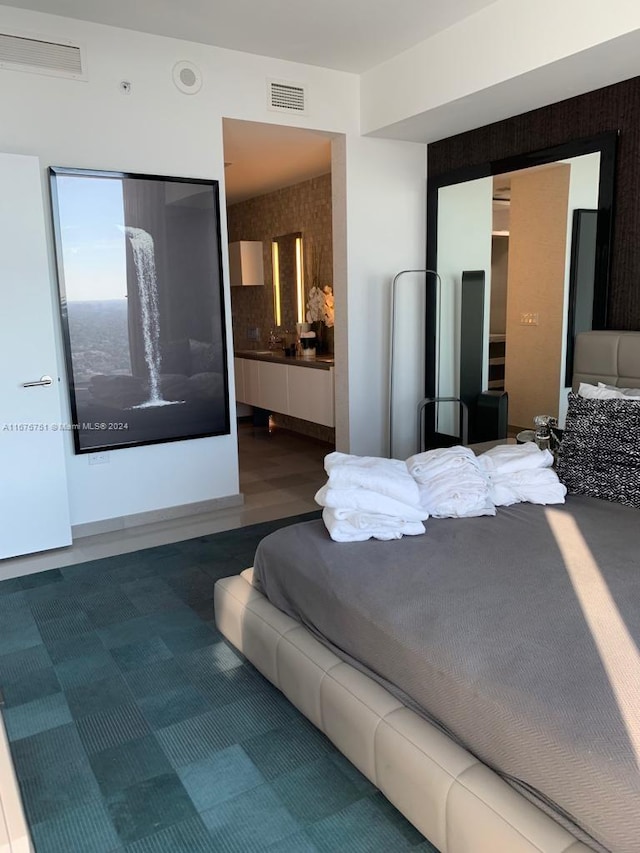 bedroom featuring ensuite bathroom and hardwood / wood-style floors