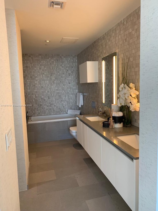 bathroom featuring vanity, tile patterned floors, a relaxing tiled tub, toilet, and tile walls