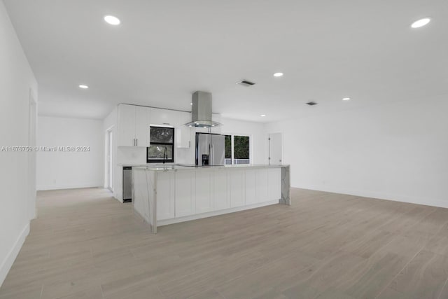 kitchen with range hood, stainless steel fridge, a center island, light wood-type flooring, and white cabinetry