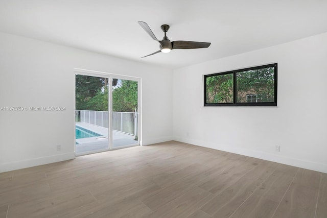 empty room with ceiling fan and light hardwood / wood-style flooring