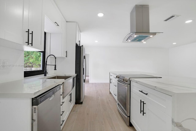 kitchen with light stone counters, white cabinetry, range hood, light hardwood / wood-style floors, and stainless steel appliances