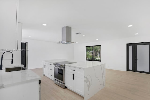 kitchen featuring wall chimney range hood, white cabinets, light stone counters, electric stove, and sink