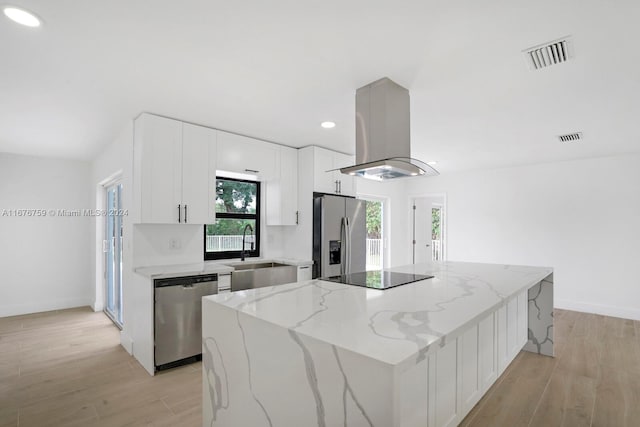 kitchen featuring light stone counters, stainless steel appliances, island range hood, and a kitchen island