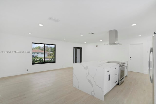 kitchen with wall chimney range hood, electric range, light stone countertops, light wood-type flooring, and white cabinetry