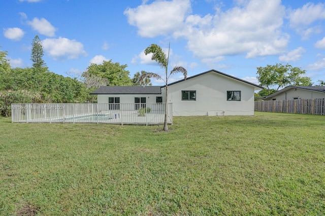 rear view of house featuring a fenced in pool and a lawn