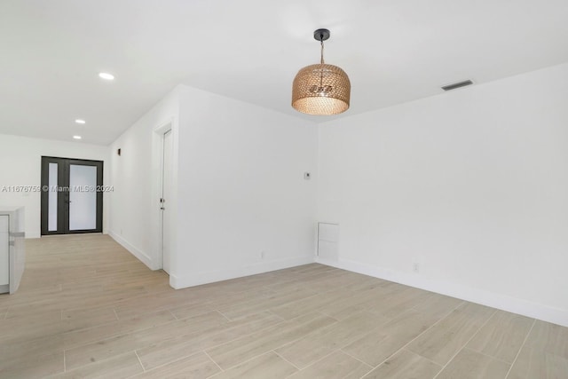 spare room with french doors and light hardwood / wood-style flooring