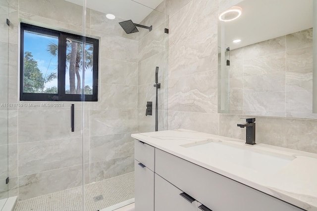 bathroom with vanity, tile walls, and a shower with door