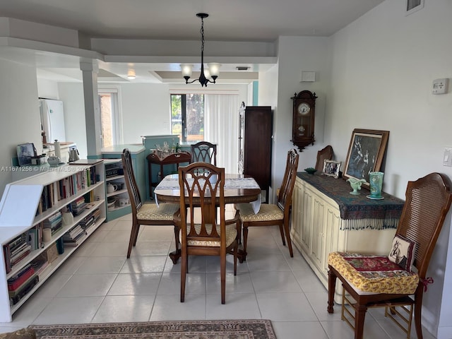 tiled dining space with a chandelier and decorative columns