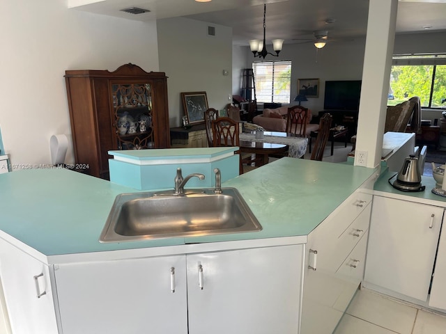 kitchen featuring light tile patterned flooring, sink, ceiling fan with notable chandelier, kitchen peninsula, and white cabinetry