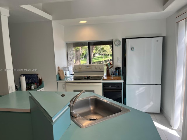 kitchen featuring sink, light tile patterned floors, and white appliances