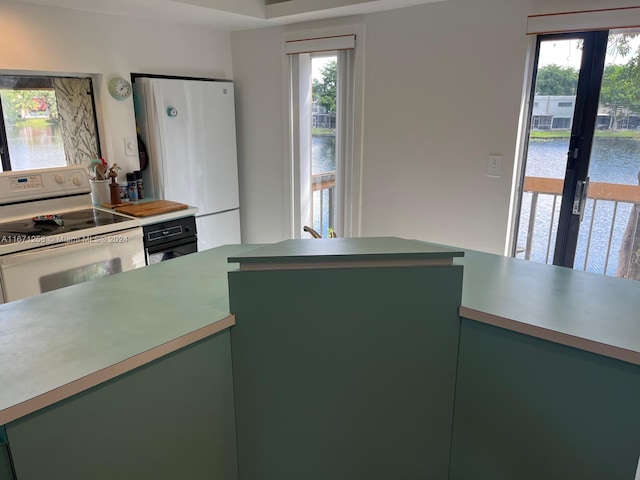 kitchen with a healthy amount of sunlight, green cabinets, a water view, and white appliances