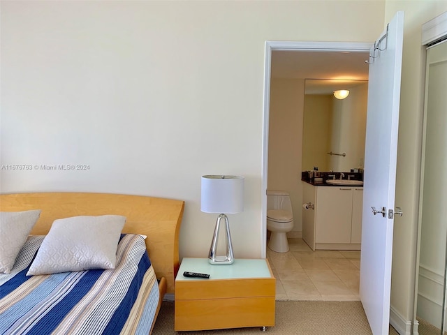 tiled bedroom featuring connected bathroom and sink