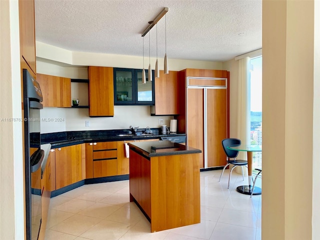 kitchen with paneled fridge, a kitchen island, sink, decorative light fixtures, and a textured ceiling