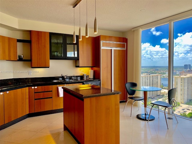 kitchen featuring hanging light fixtures, a kitchen island, a textured ceiling, light tile patterned flooring, and sink