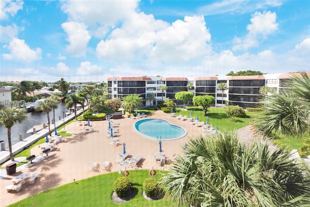 view of swimming pool with a patio area, a lawn, and a water view