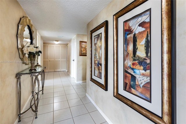 corridor with a textured ceiling and light tile patterned flooring