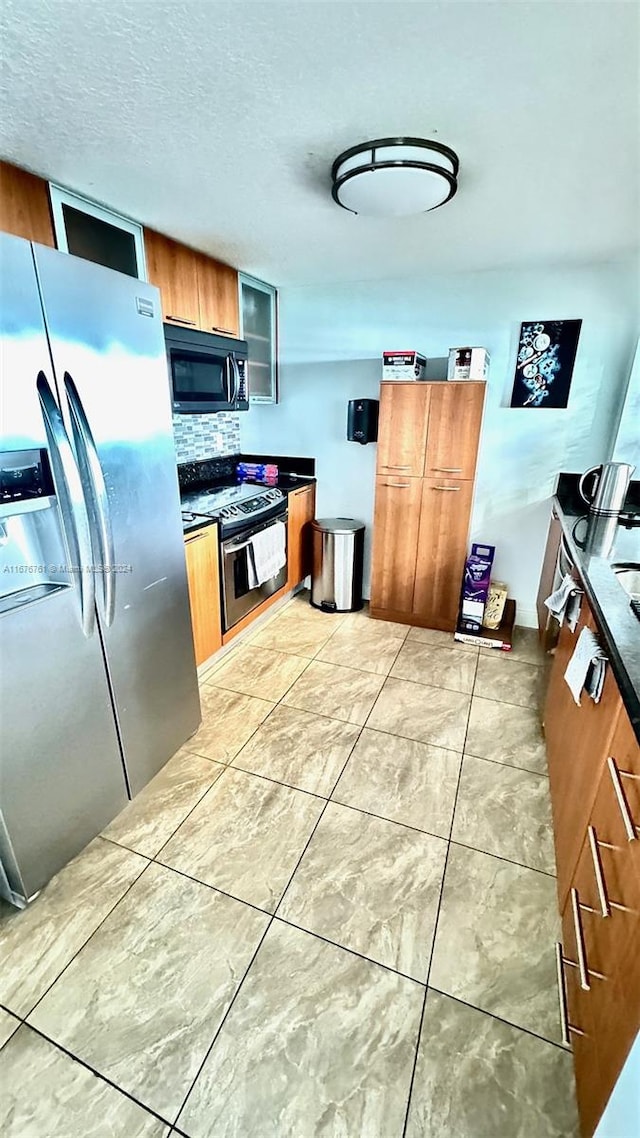 kitchen featuring decorative backsplash, appliances with stainless steel finishes, a textured ceiling, and light tile patterned flooring