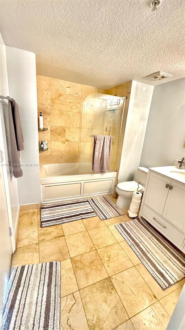 full bathroom with vanity, tiled shower / bath combo, a textured ceiling, and toilet