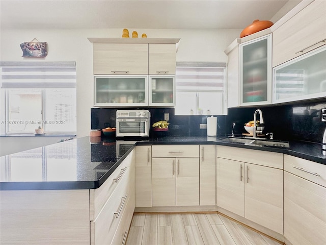 kitchen with light hardwood / wood-style flooring, decorative backsplash, and sink