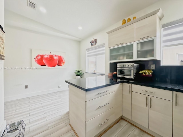 kitchen with lofted ceiling, stainless steel oven, kitchen peninsula, and cream cabinets