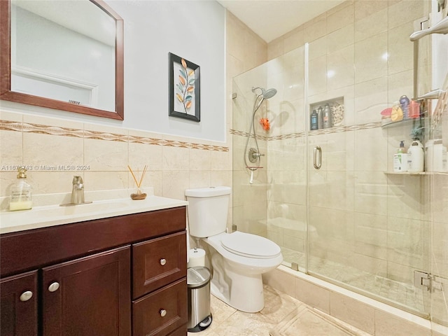 bathroom with toilet, tile patterned flooring, vanity, tile walls, and walk in shower