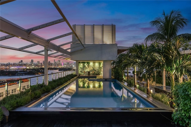 pool at dusk featuring a city view and an outdoor pool