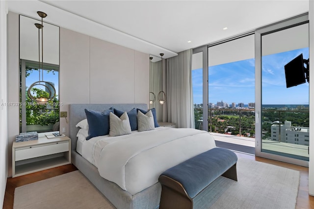 bedroom featuring access to exterior, expansive windows, multiple windows, and light wood-type flooring