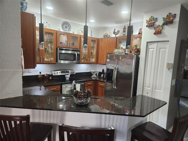 kitchen with a kitchen bar, kitchen peninsula, hanging light fixtures, and appliances with stainless steel finishes