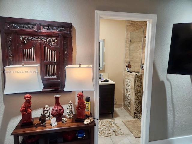 interior space featuring tiled shower, vanity, and tile patterned floors